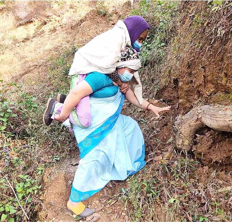 Lila Thapa, a health worker from Gulmi district in western Nepal, carries an elderly woman, Tadan, to her COVID-19 vaccination.