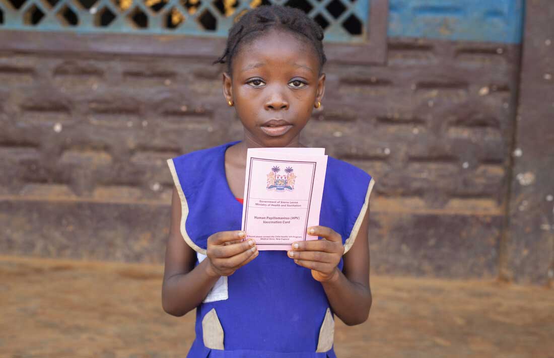 A girl holds a vaccination card in Sierra Leone. Credit: Gavi/2022/Joshua Kamara.