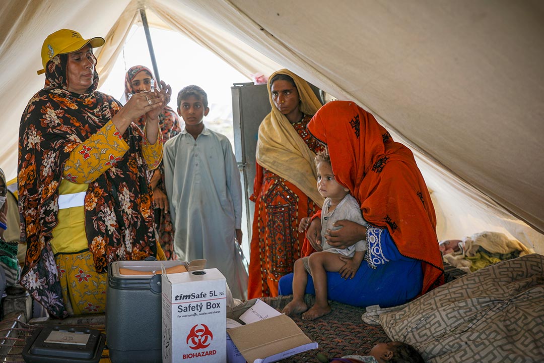 Hakim Zadi (left), a trained midwife prepares a TCV shot for Tahseen, aged two. In Sohbatpur city, as in other parts of Pakistan, many displaced families are sheltering in tents after the summer’s floods inundated their homes. Credit Gavi/Asad Zaidi.