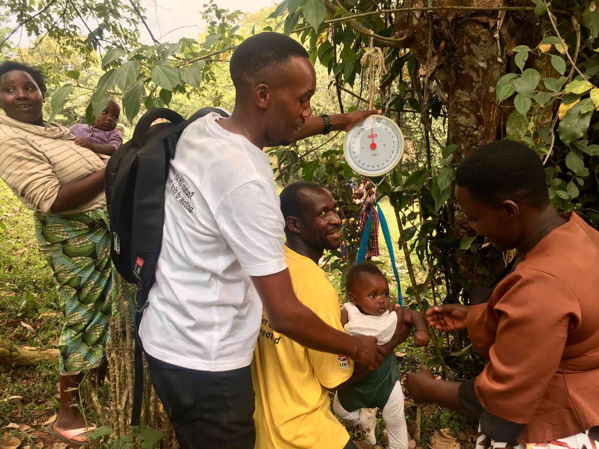 A community health worker  from InPact-Uganda (in white) helping to take a baby's weight in Kajugangoma village in Kanungu. Credit: John Agaba